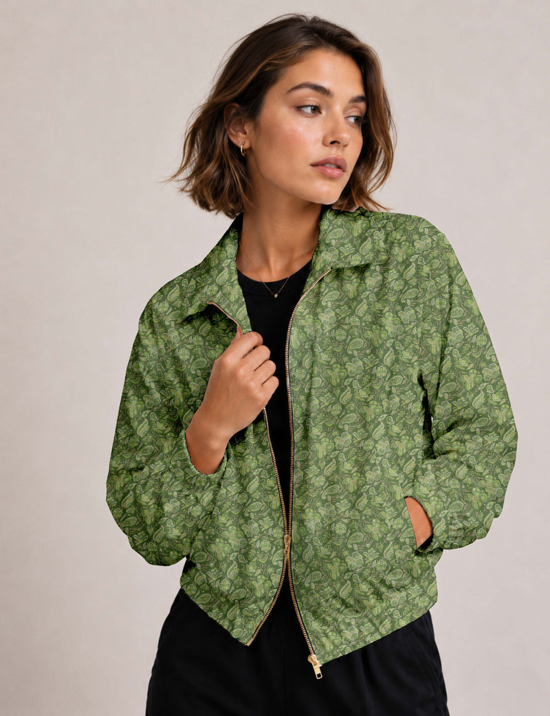 Woman wearing green tropical patterned bomber jacket with gold zipper and elastic cuffs, shown from front waist up