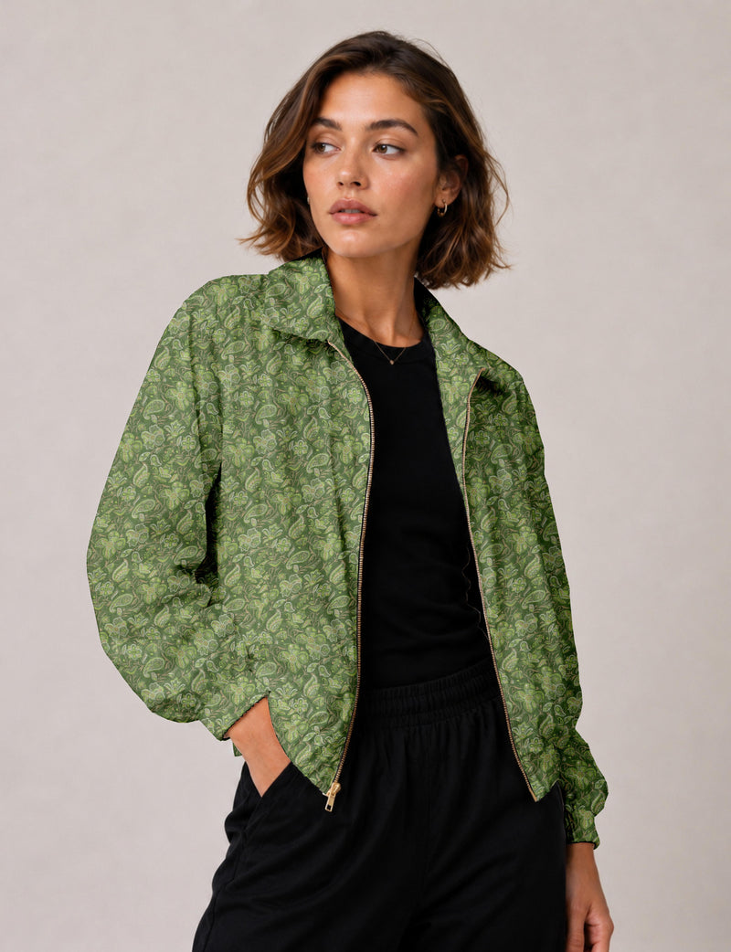 Woman wearing a green tropical patterned bomber jacket with a front zipper, shown from the front and side angle