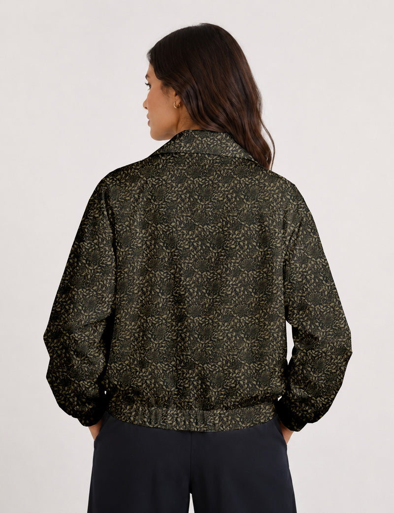 Woman wearing a yellow floral bomber jacket with front zipper, elastic cuffs, and side pockets, shown from front view