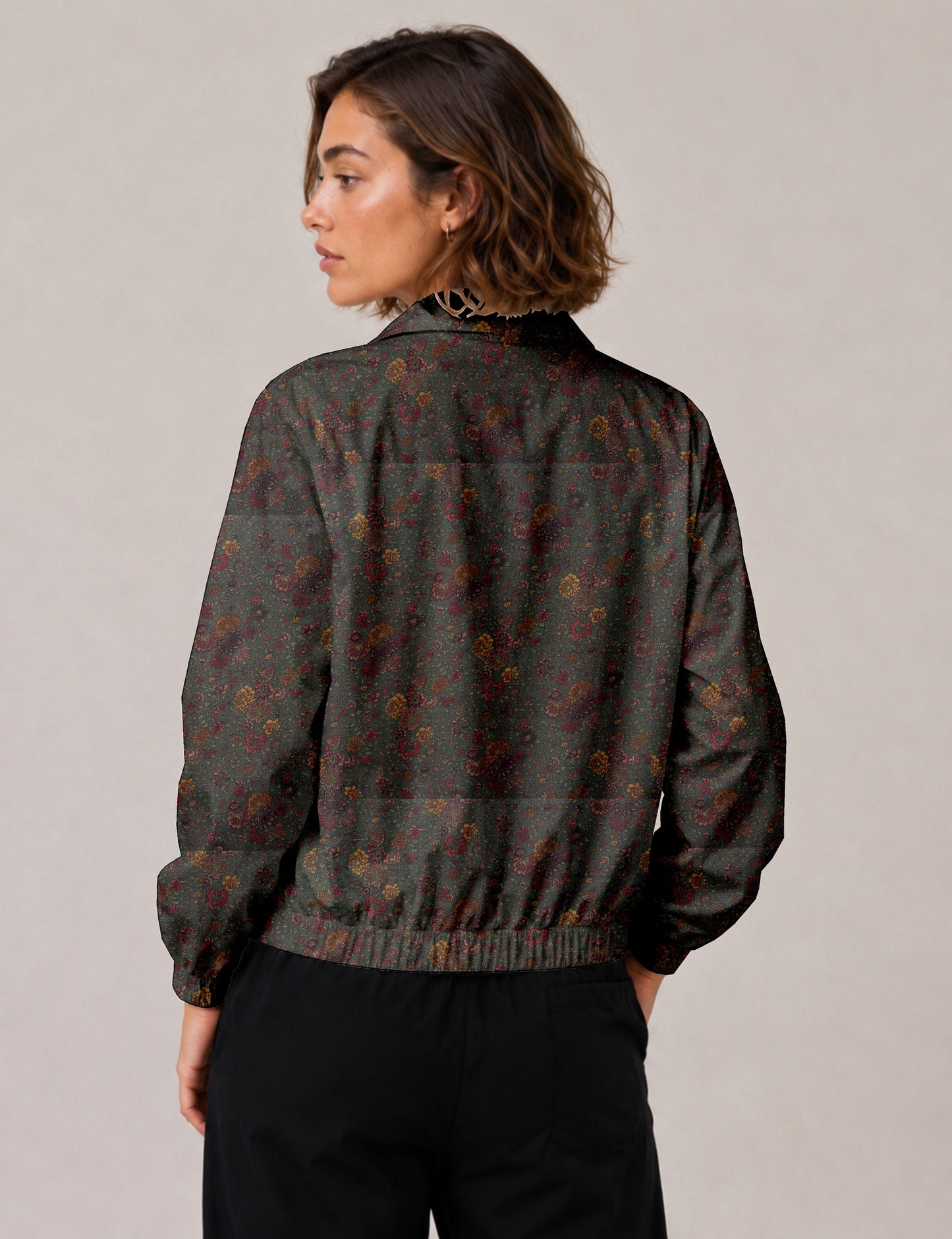 Woman wearing a yellow floral bomber jacket with front zipper, elastic cuffs, and side pockets, shown from front view