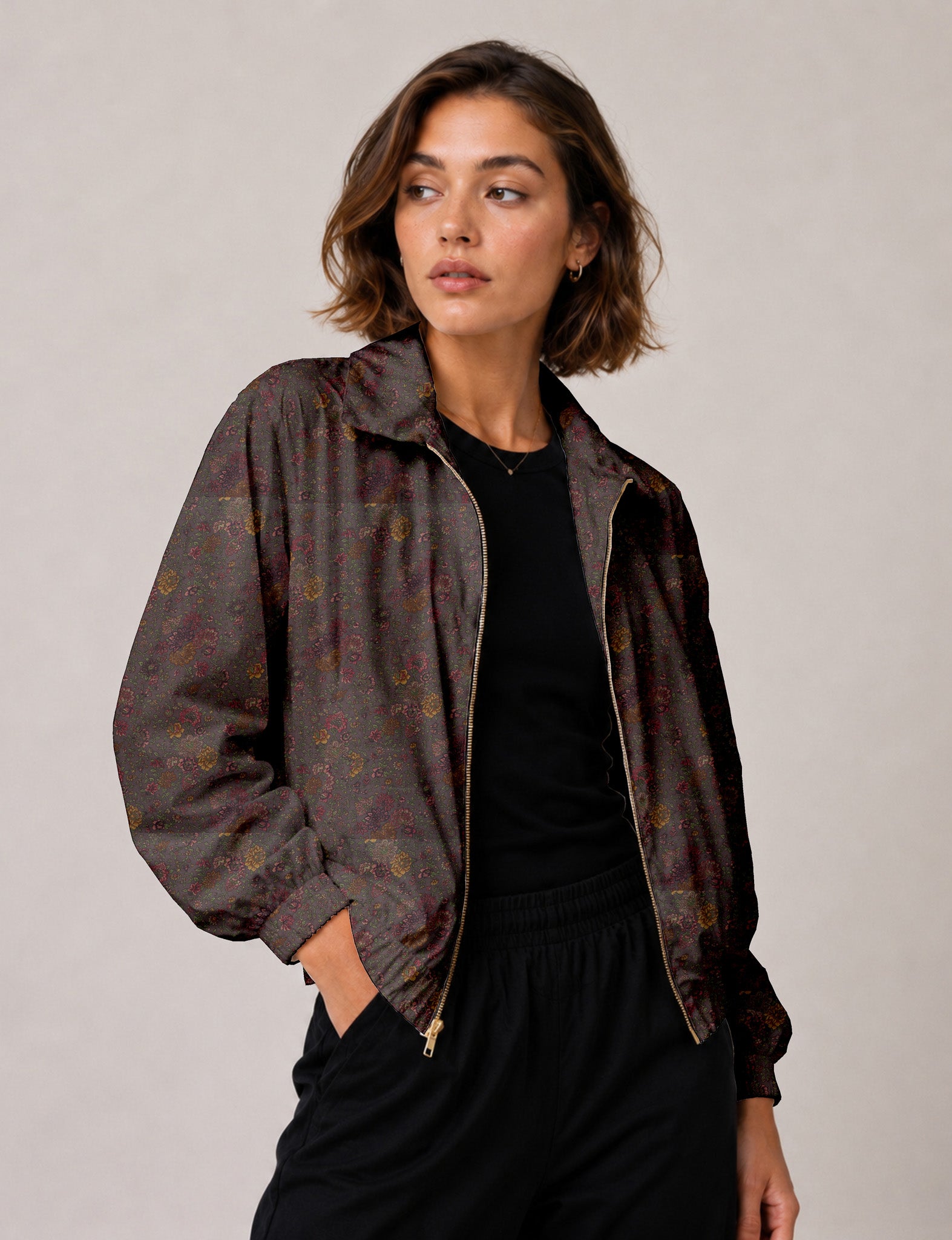 Woman wearing a yellow floral bomber jacket with front zipper, elastic cuffs, and side pockets, shown from front view