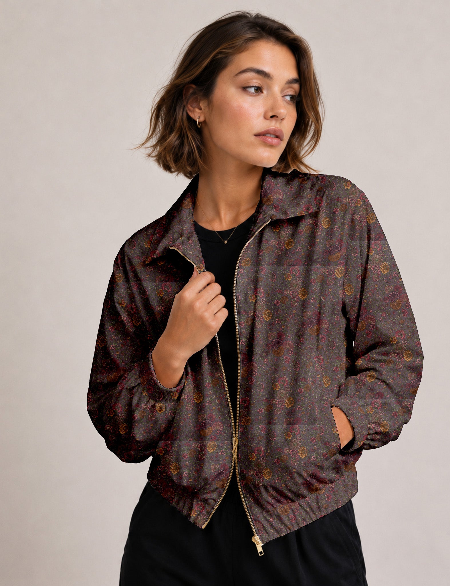 Brown floral bomber jacket with front zipper, elastic cuffs and hem, hanging on white hanger, red floral inner lining visible