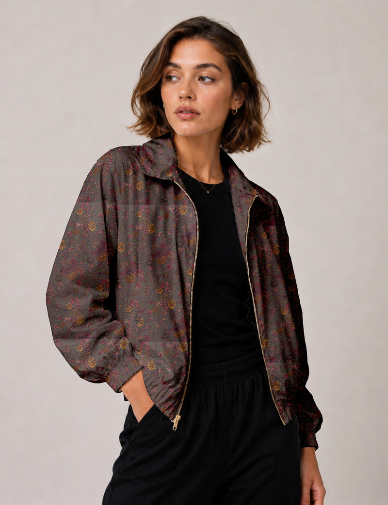 Woman wearing a yellow floral bomber jacket with front zipper, elastic cuffs, and side pockets, shown from front view