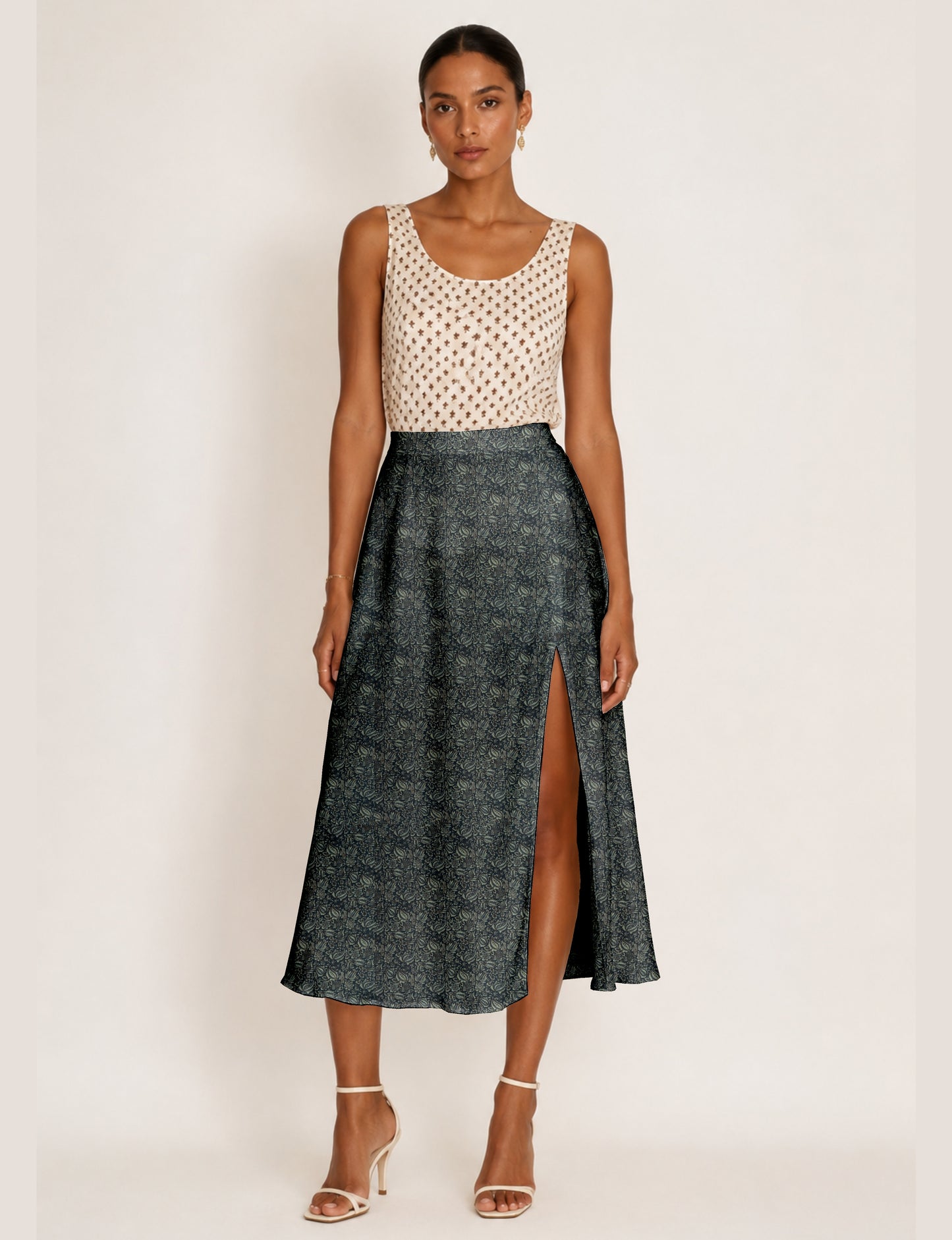 Woman wearing a yellow and black micro patterned A-line skirt with front slit, paired with beige sleeveless top and black