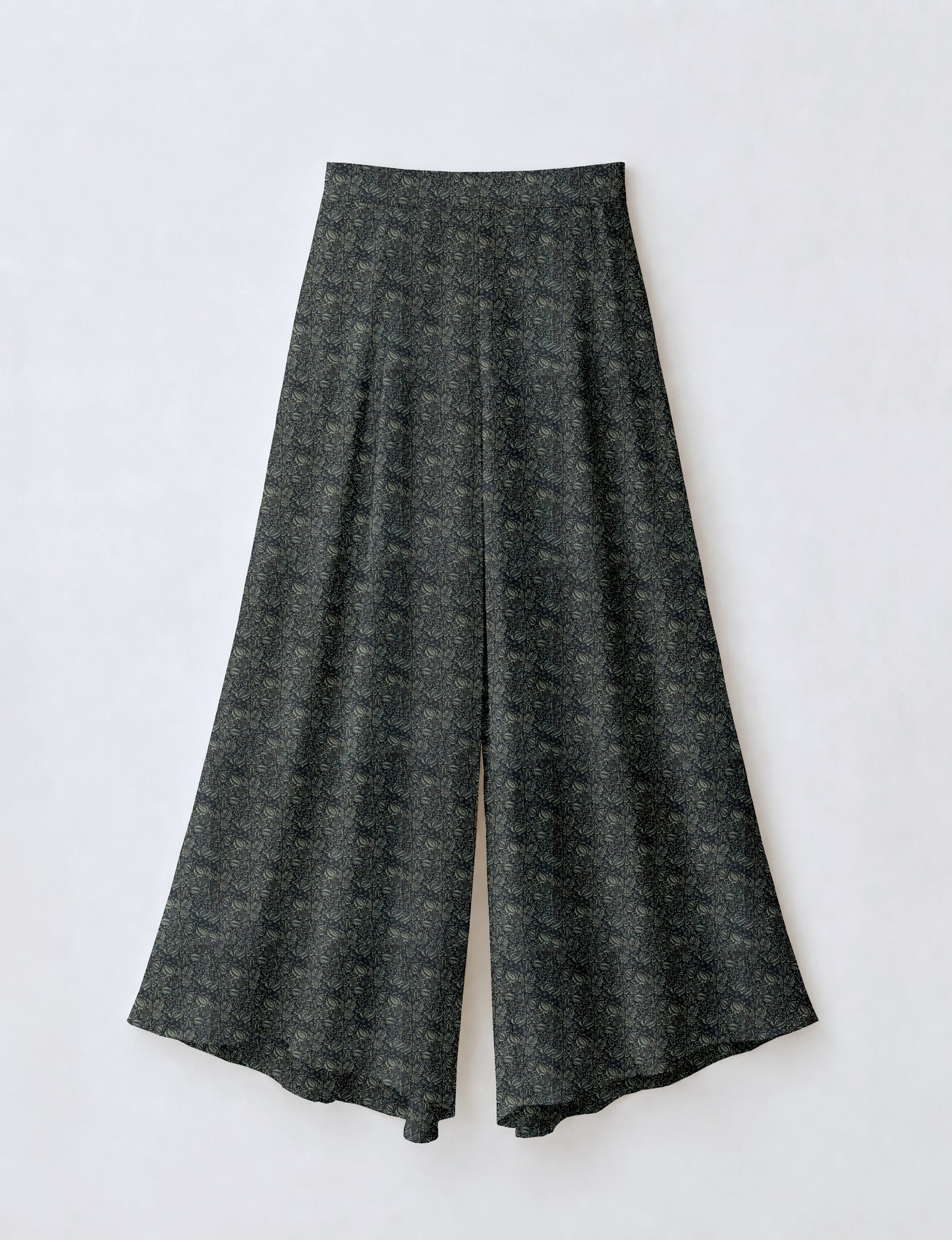 Woman wearing blue wide leg palazzo trousers with black and brown floral print, paired with brown sleeveless top and white