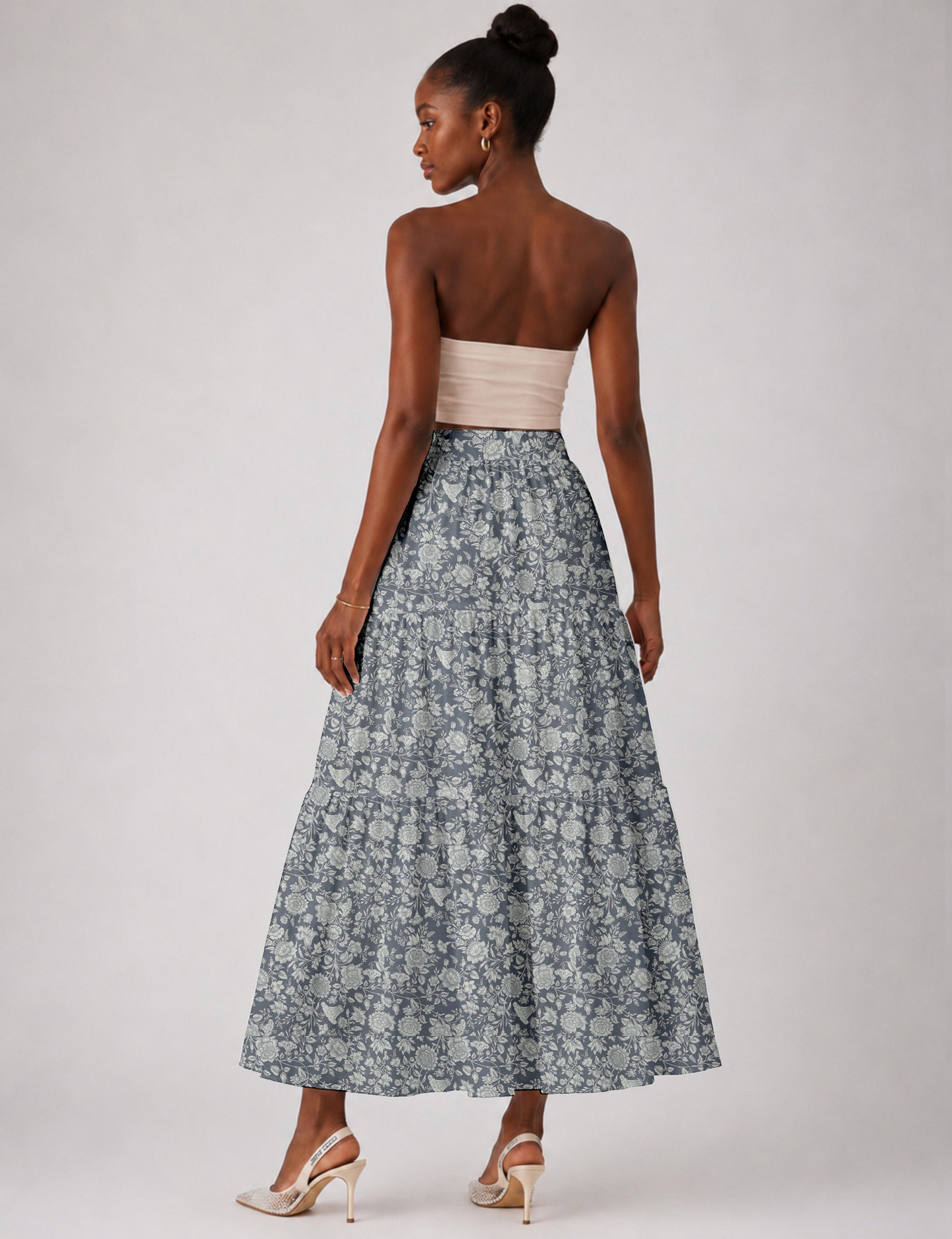 Woman wearing a yellow midi tiered skirt with a small geometric pattern, shown from the back, paired with beige top and