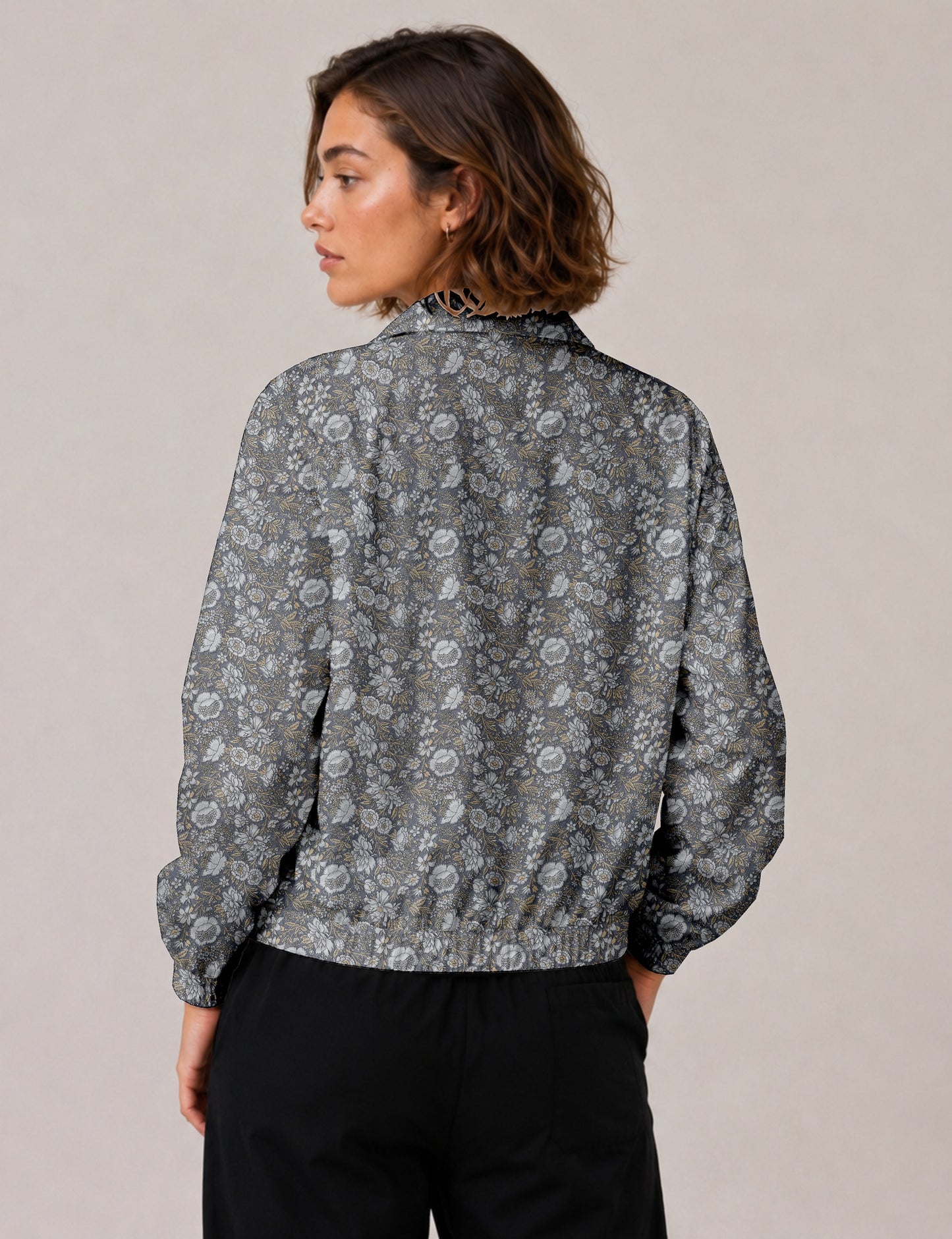 Woman wearing a yellow floral bomber jacket with front zipper, elastic cuffs, and side pockets, shown from front view