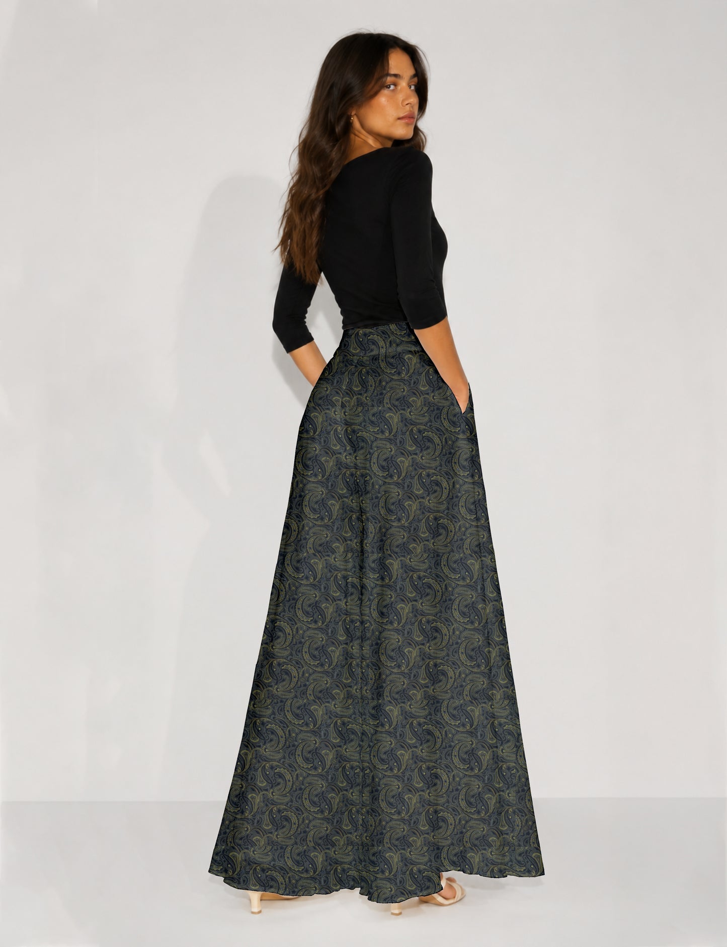 Woman wearing blue wide leg palazzo trousers with black and brown floral print, paired with brown sleeveless top and white
