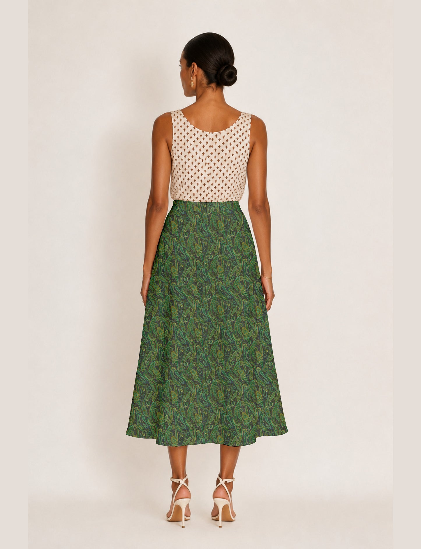 Woman wearing a yellow and black micro patterned A-line skirt with front slit, paired with beige sleeveless top and black
