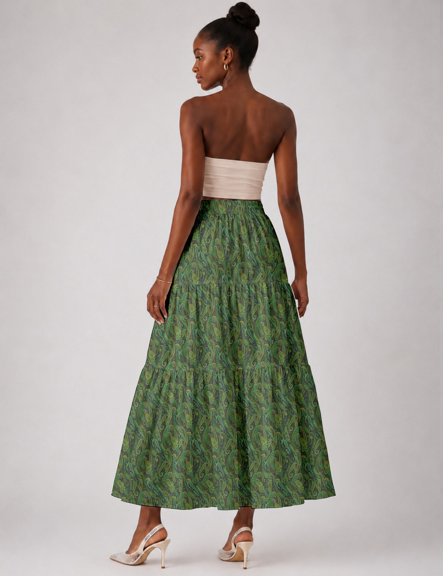 Woman wearing a yellow midi tiered skirt with a small geometric pattern, paired with a beige strapless top and white heels