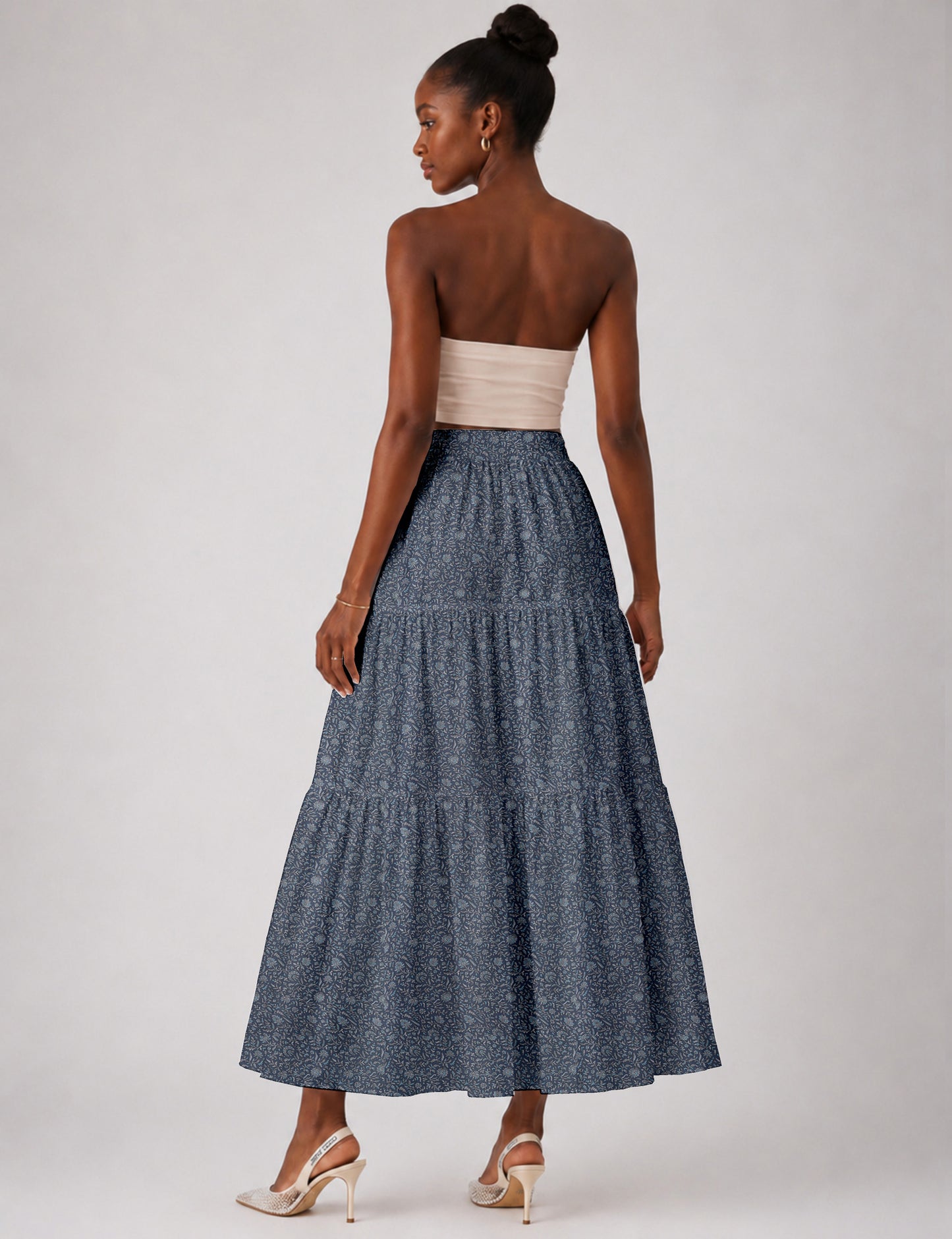 Woman wearing a yellow midi tiered skirt with a small geometric pattern, paired with a beige strapless top and white heels