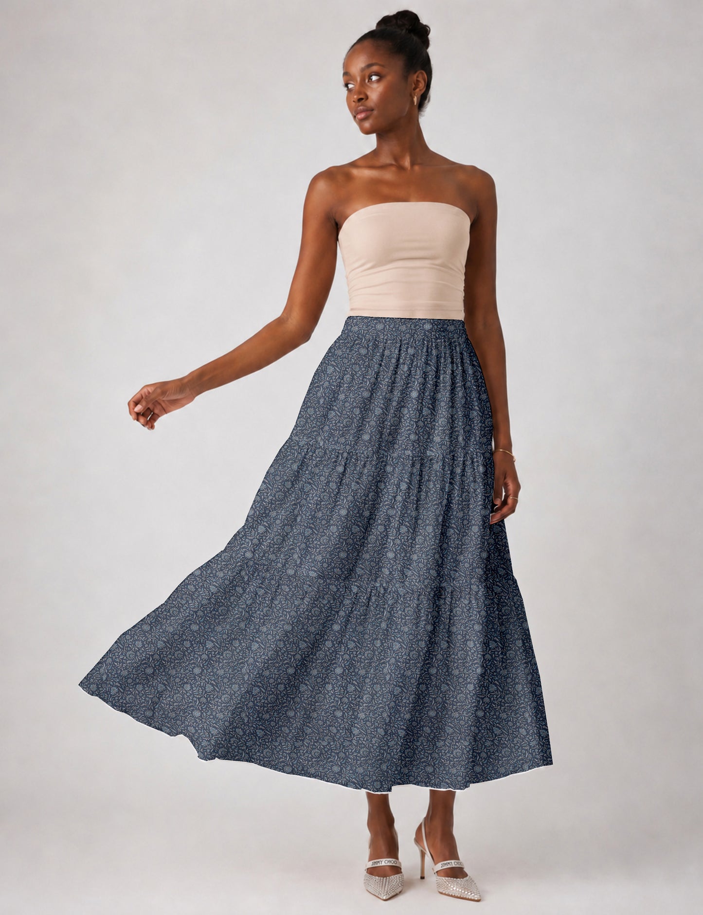 Woman wearing a yellow midi tiered skirt with a small geometric pattern, shown from the back, paired with beige top and