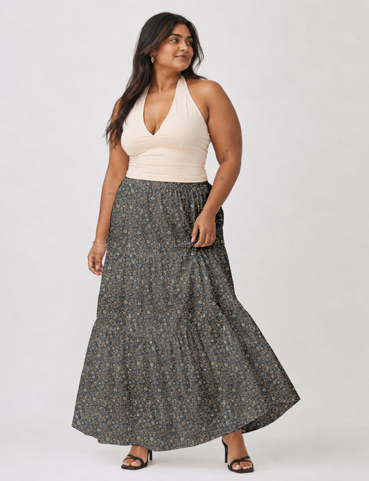 Woman wearing a yellow midi tiered skirt with a small geometric pattern, paired with a beige strapless top and white heels