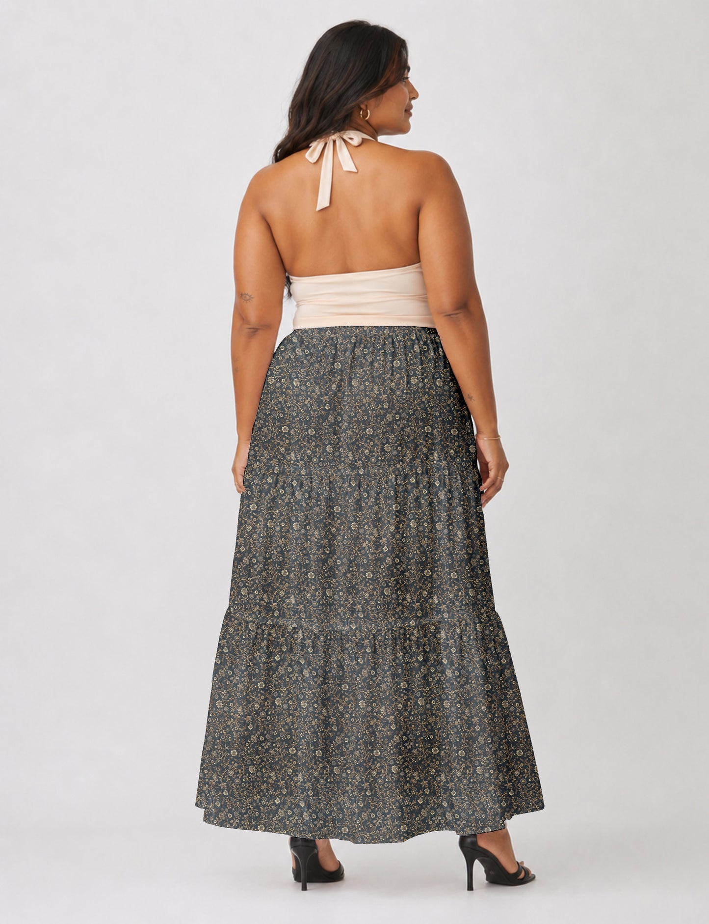 Woman wearing a yellow midi tiered skirt with a small geometric pattern, shown from the back, paired with beige top and