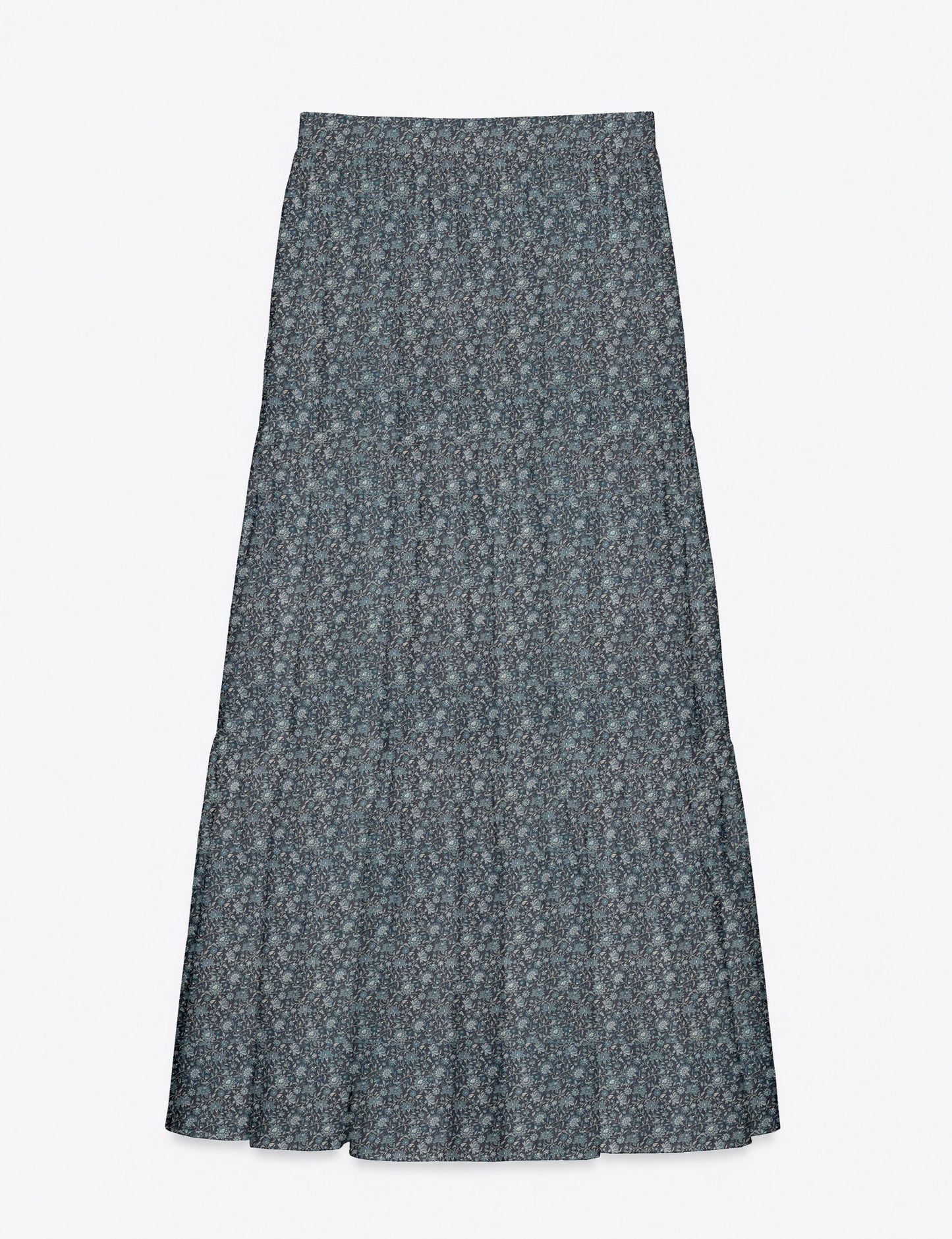 Woman wearing a yellow midi tiered skirt with a small geometric pattern, paired with a beige strapless top and white heels