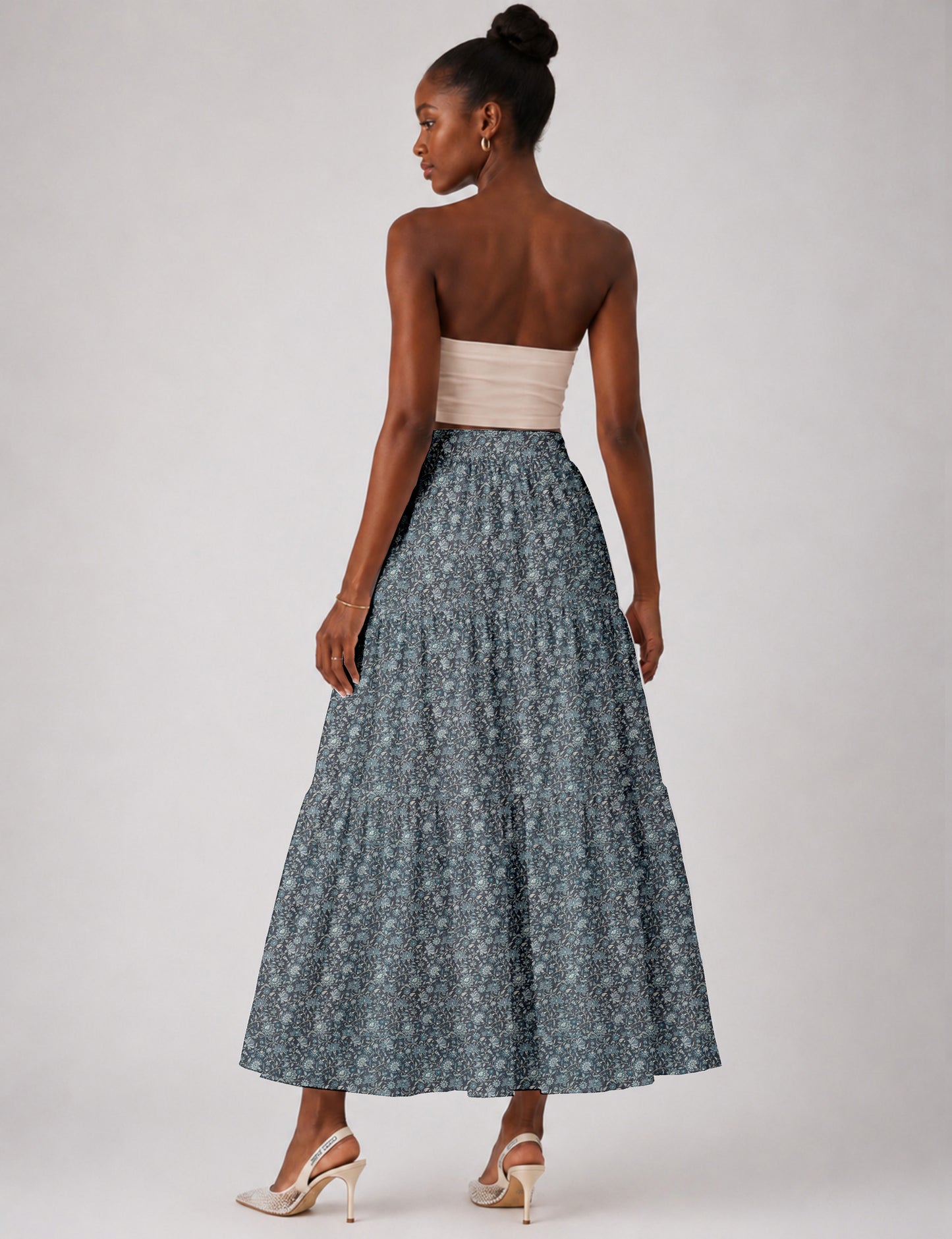 Woman wearing a yellow midi tiered skirt with a small geometric pattern, shown from the back, paired with beige top and