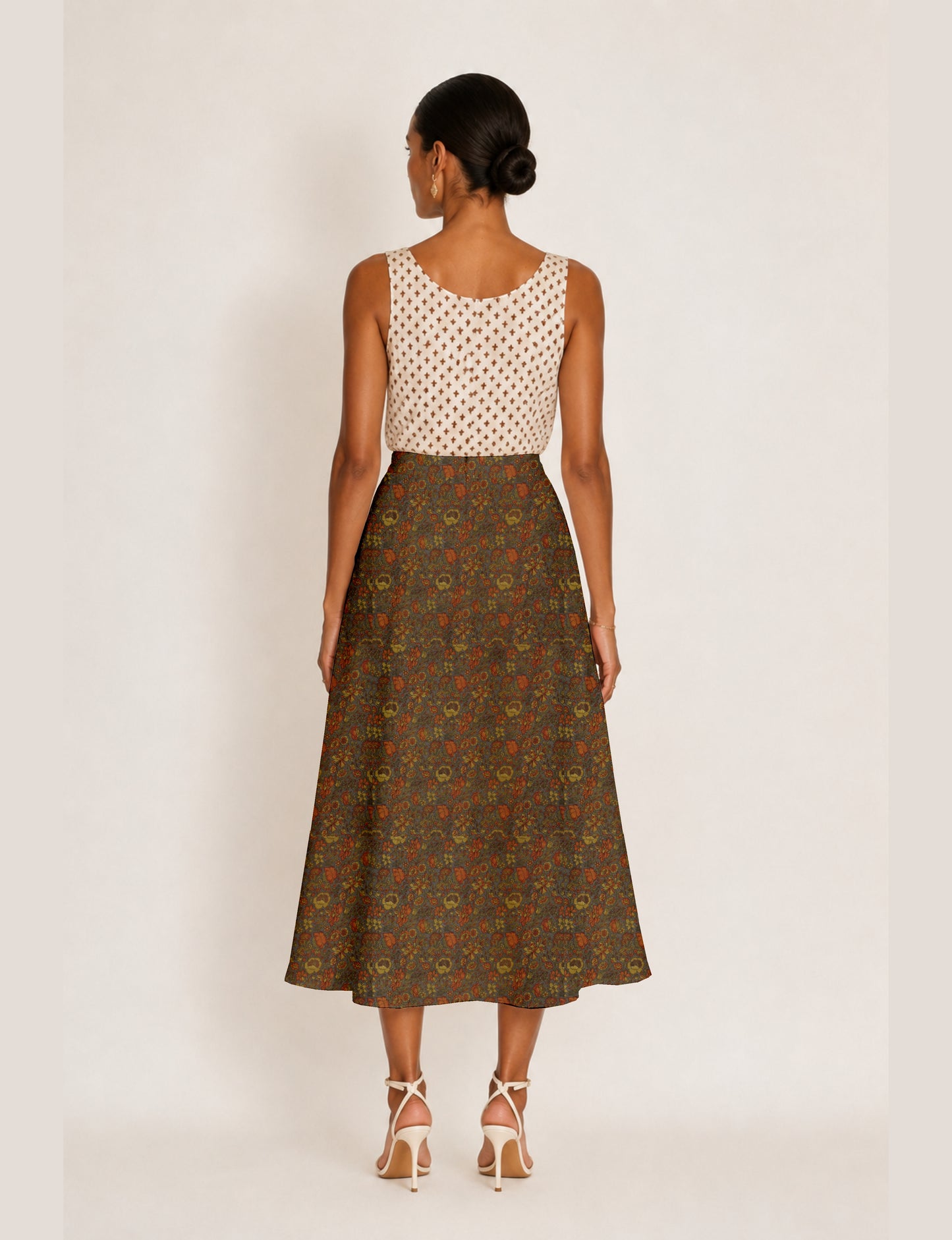 Woman wearing a yellow and black micro patterned A-line skirt with front slit, paired with beige sleeveless top and black