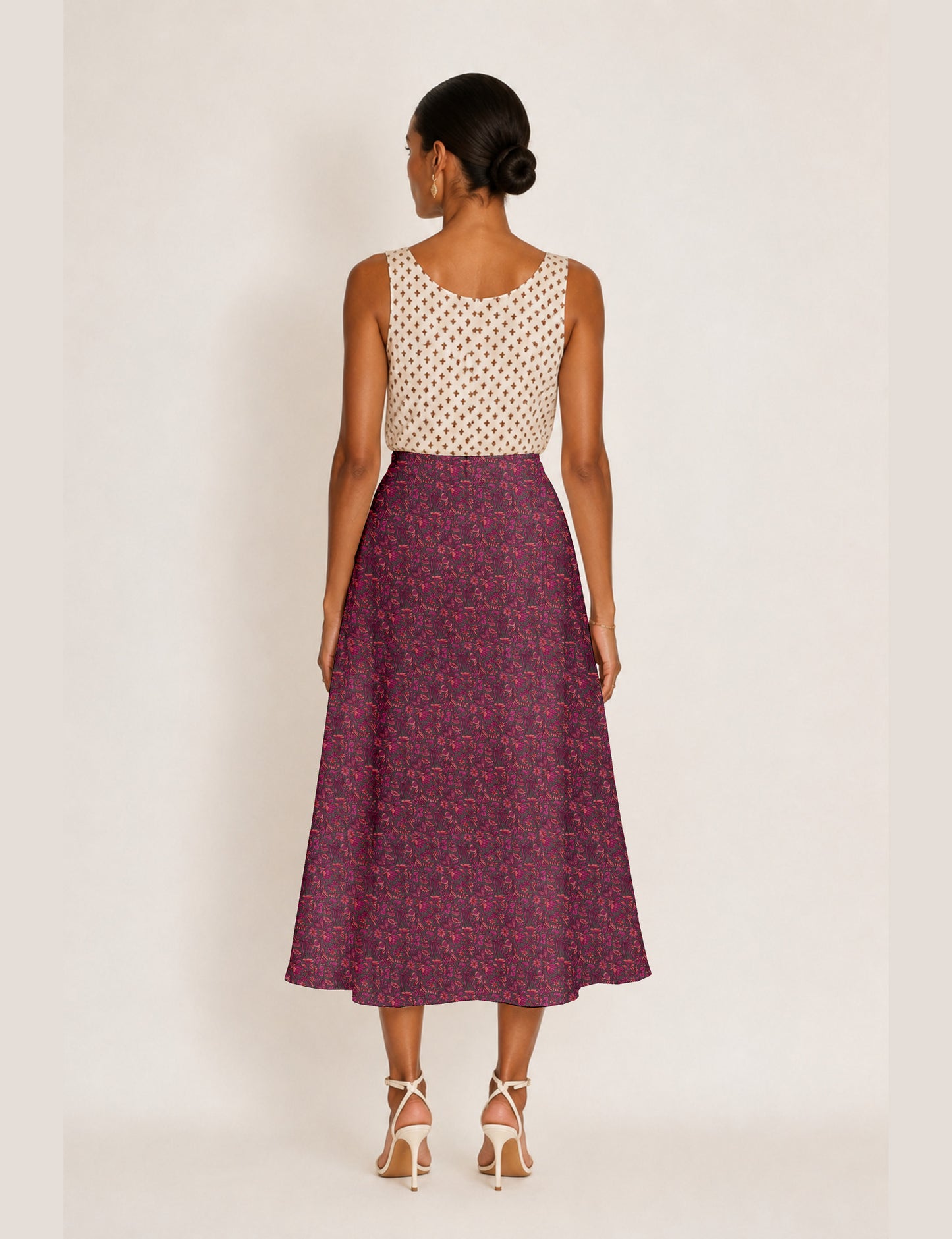 Woman wearing a yellow and black micro patterned A-line skirt with front slit, paired with beige sleeveless top and black