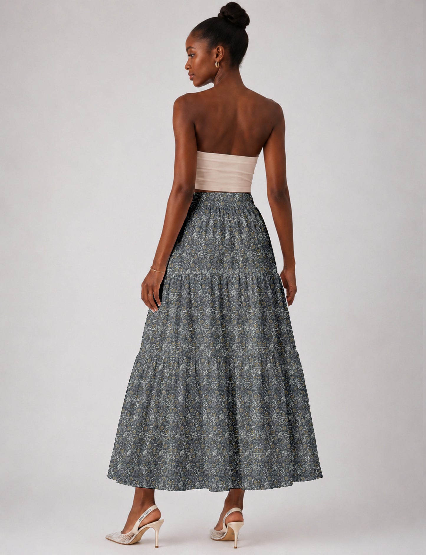 Woman wearing a yellow midi tiered skirt with a small geometric pattern, paired with a beige strapless top and white heels