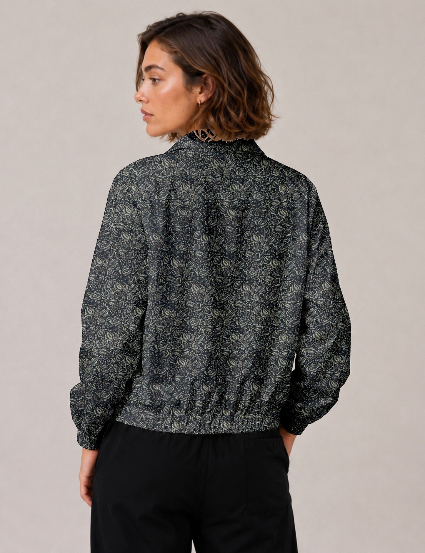 Woman wearing a yellow floral bomber jacket with front zipper, elastic cuffs, and side pockets, shown from front view
