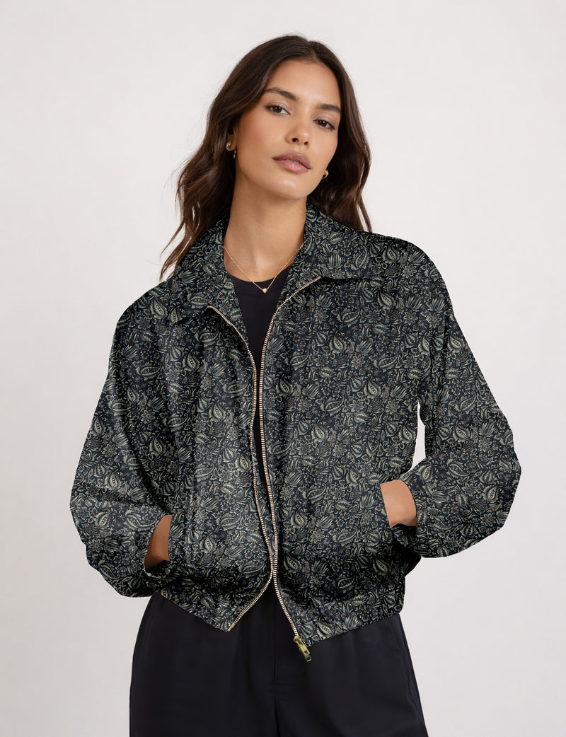 Woman wearing a yellow floral bomber jacket with front zipper, elastic cuffs, and side pockets, shown from front view