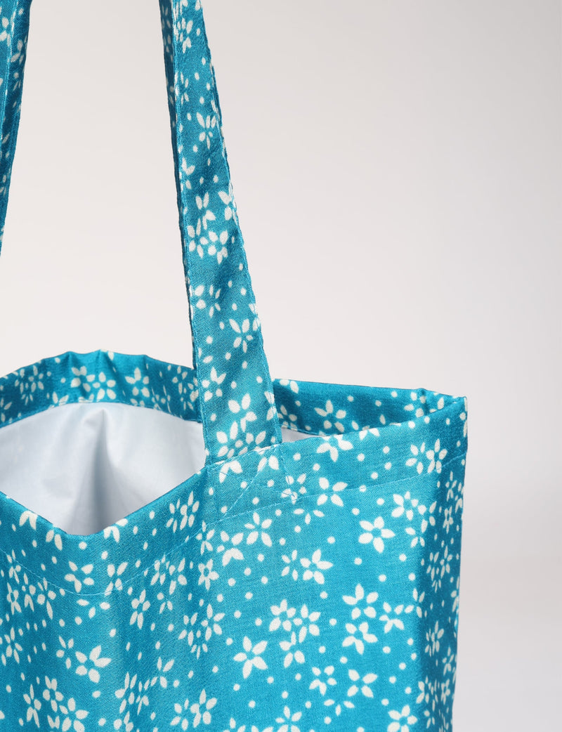 Blue floral patterned fabric shopper bag with matching handles, shown in close-up front view with white interior lining visible