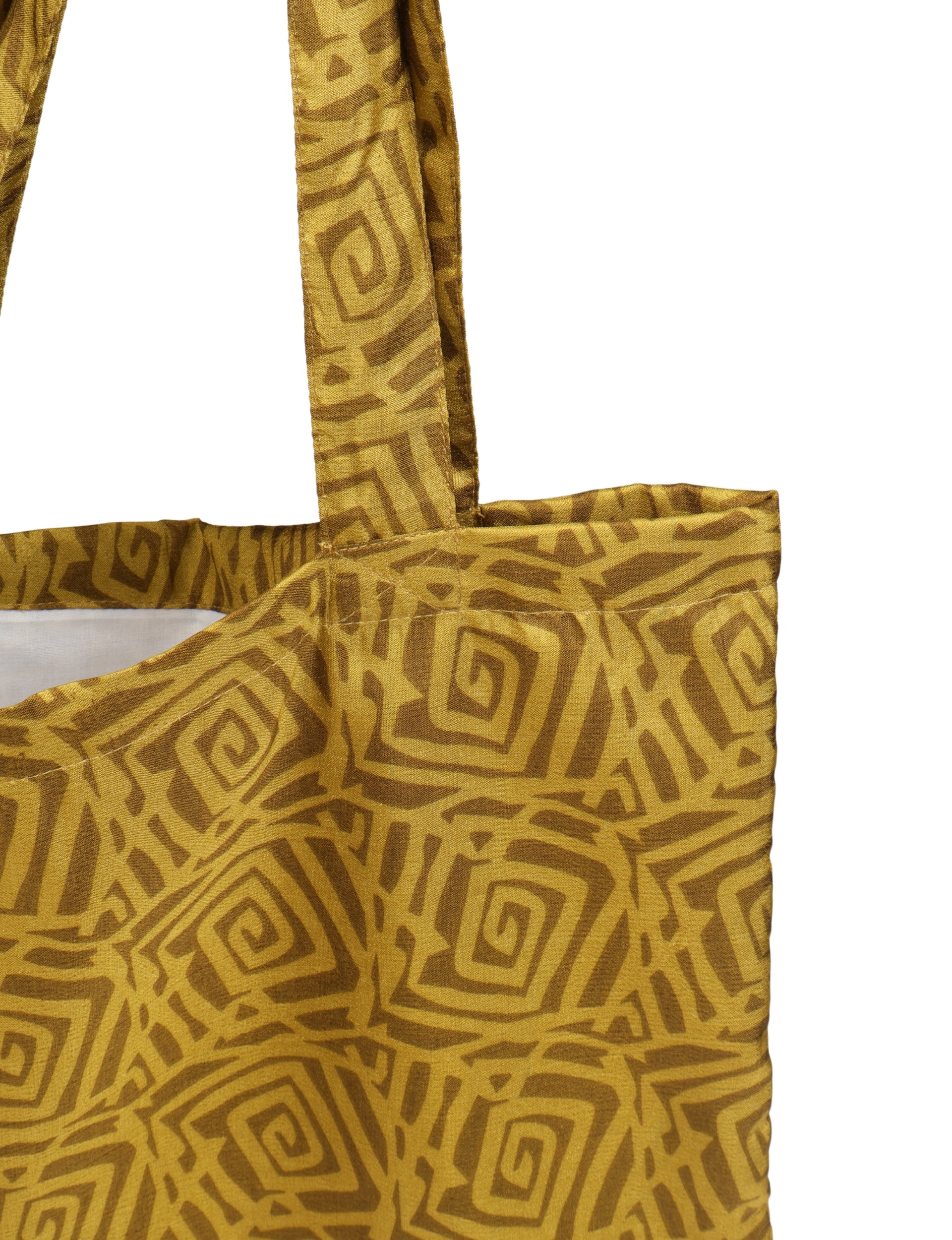 Yellow shopper bag with dark yellow geometric spiral pattern, fabric texture visible, showing top corner and strap close-up