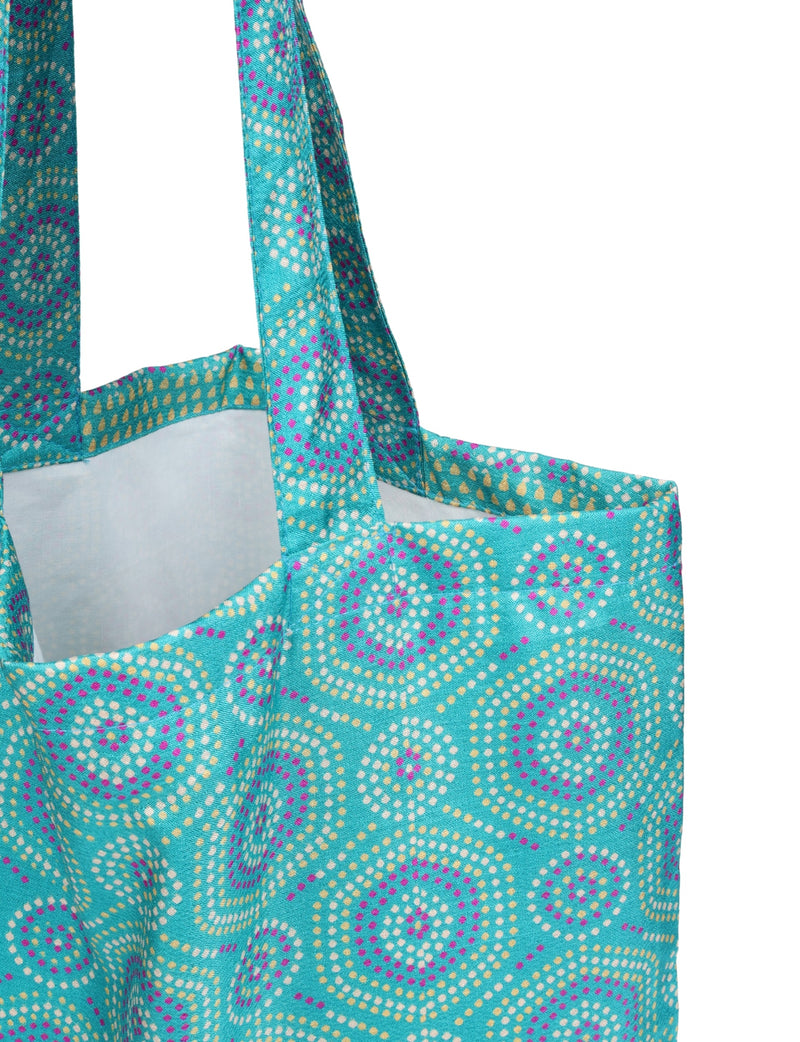 Blue shopper bag with Indian ethnic circular dot pattern in pink, white, and gold, shown in close-up front view with handles