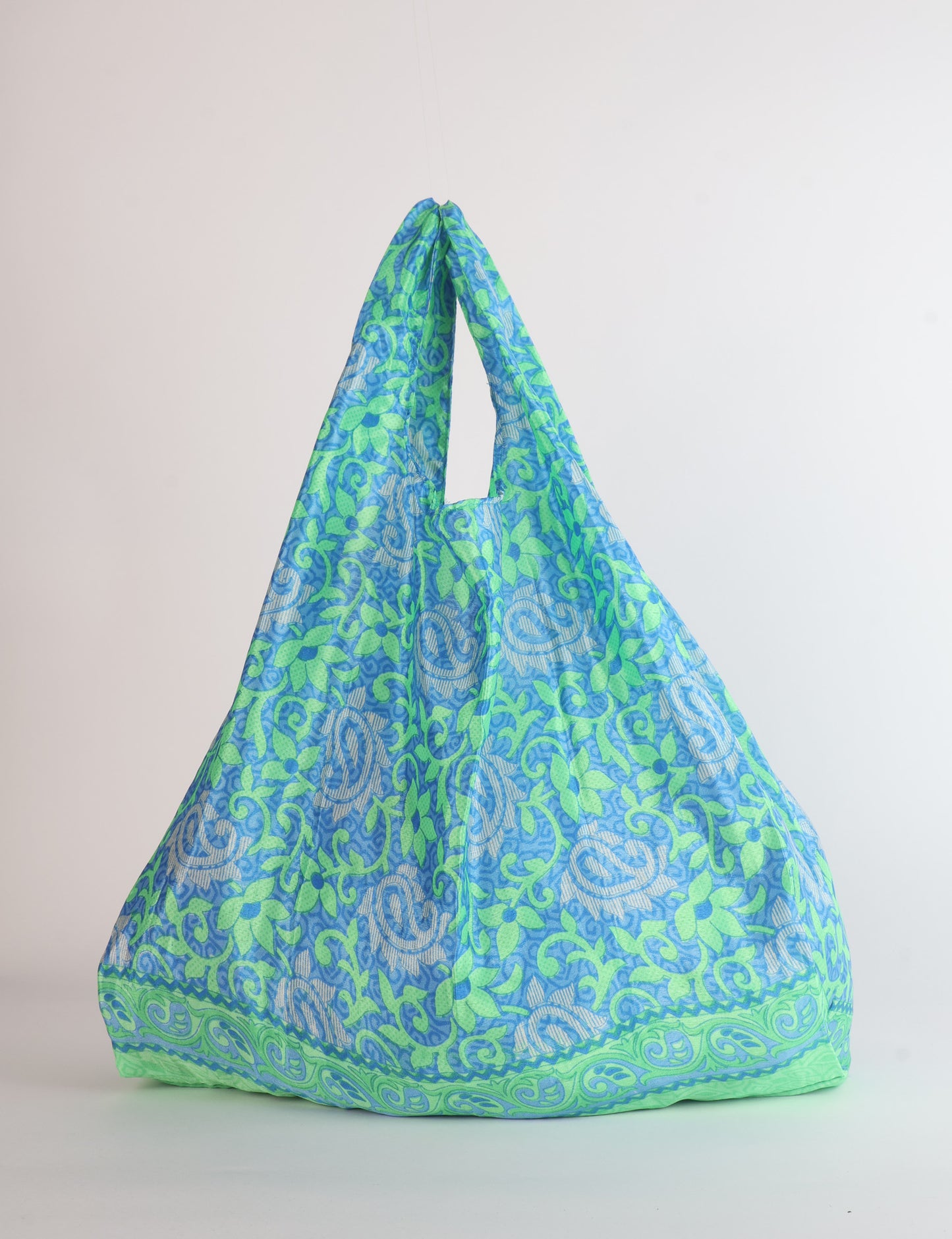Stay eco-conscious with our Reusable Bag, handmade by Indian artisans from pre-loved saris. Silky and lightweight, this foldaway bag is perfect for your on-the-go lifestyle. Each piece is a unique statement of ethical fashion, embracing sustainability and style.