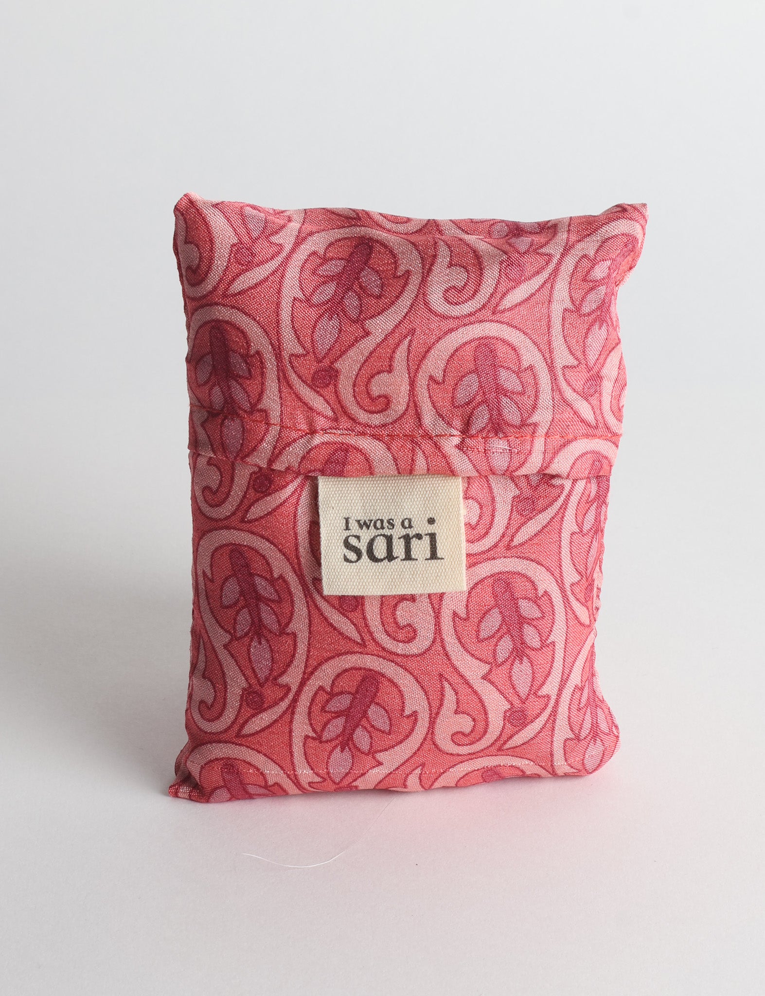 Pink reusable bag with paisley pattern and a fabric label reading "I was a sari" shown folded against white background