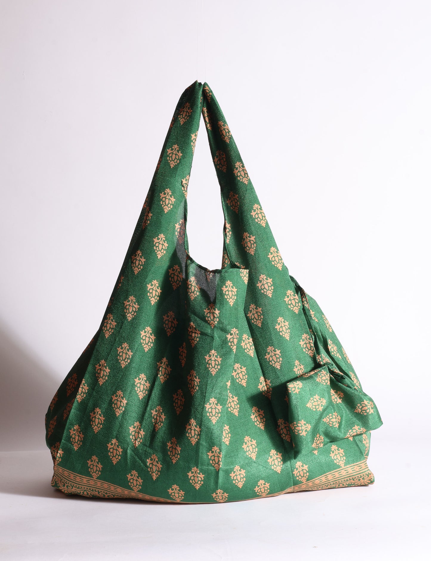Blue reusable bag with tropical floral pattern in pink, yellow, and green, shown hanging with handles visible