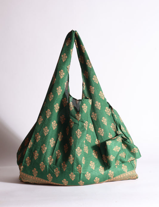 Blue reusable bag with tropical floral pattern in pink, yellow, and green, shown hanging with handles visible