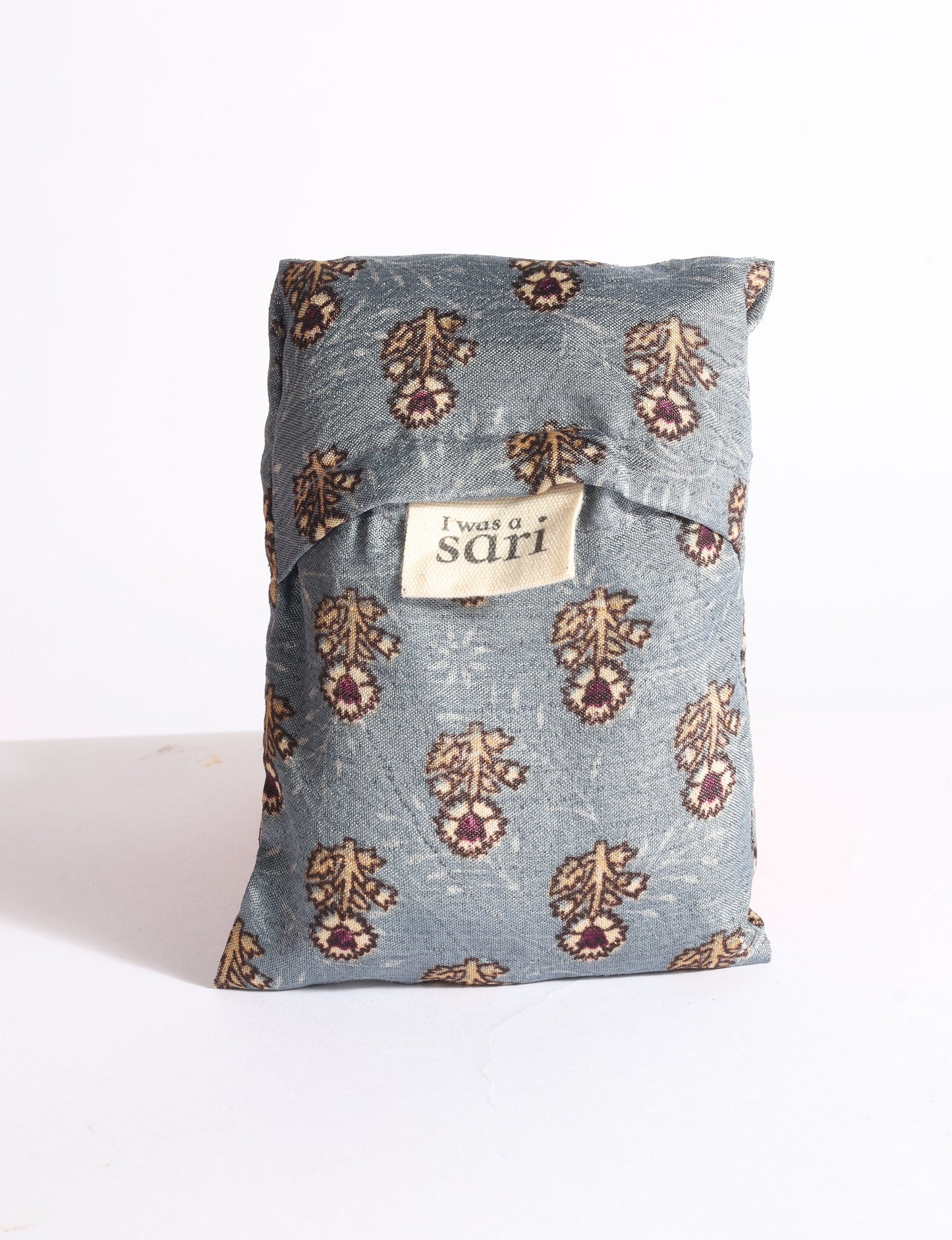 Blue reusable bag with multicolor tropical floral pattern folded with "I was a sari" label visible on front