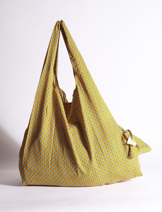 Blue reusable bag with tropical floral pattern in pink, yellow, and green, shown hanging with handles visible