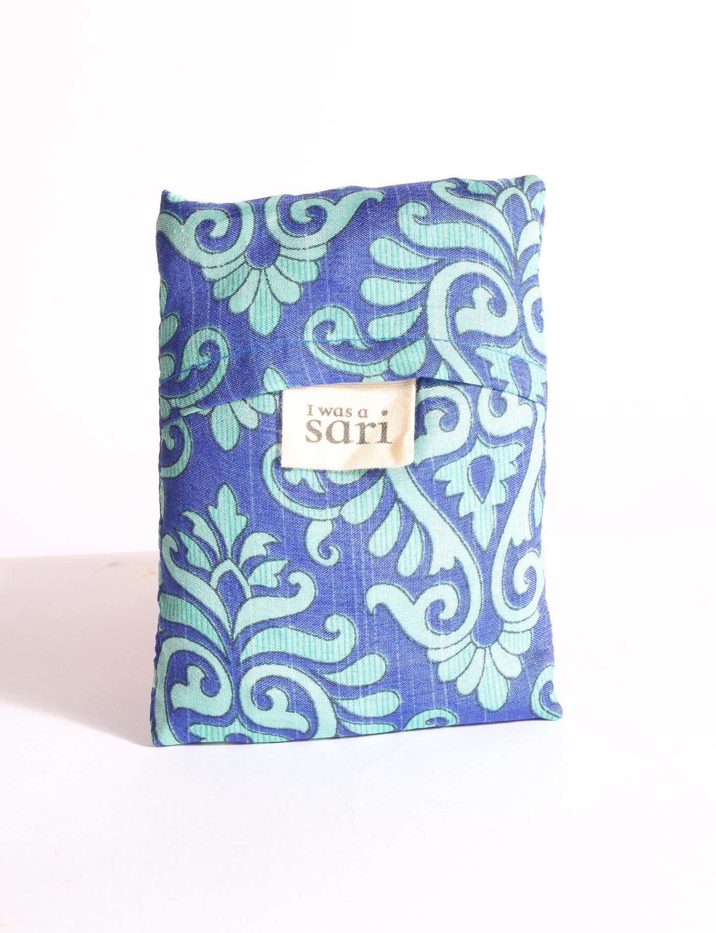Blue reusable bag with multicolor tropical floral pattern folded with "I was a sari" label visible on front
