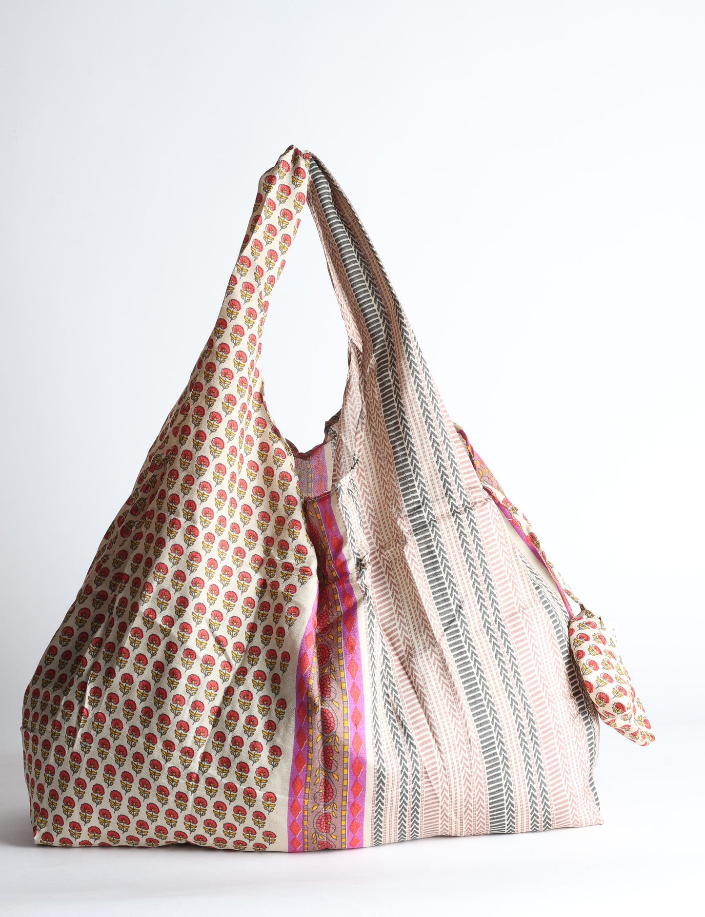 Blue reusable bag with tropical floral pattern in pink, yellow, and green, shown hanging with handles visible