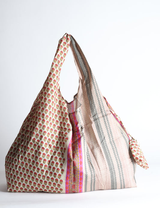 Blue reusable bag with tropical floral pattern in pink, yellow, and green, shown hanging with handles visible