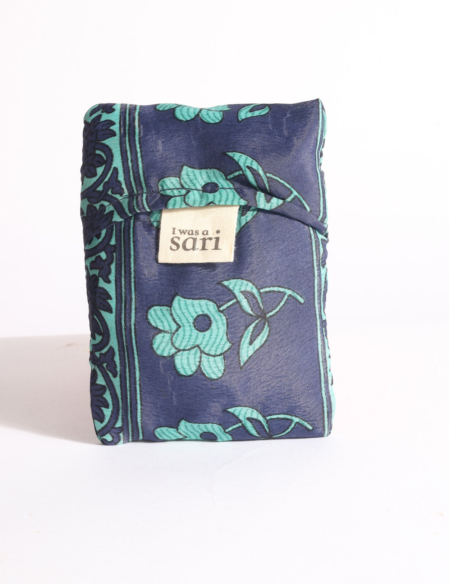 Blue reusable bag with multicolor tropical floral pattern folded with "I was a sari" label visible on front