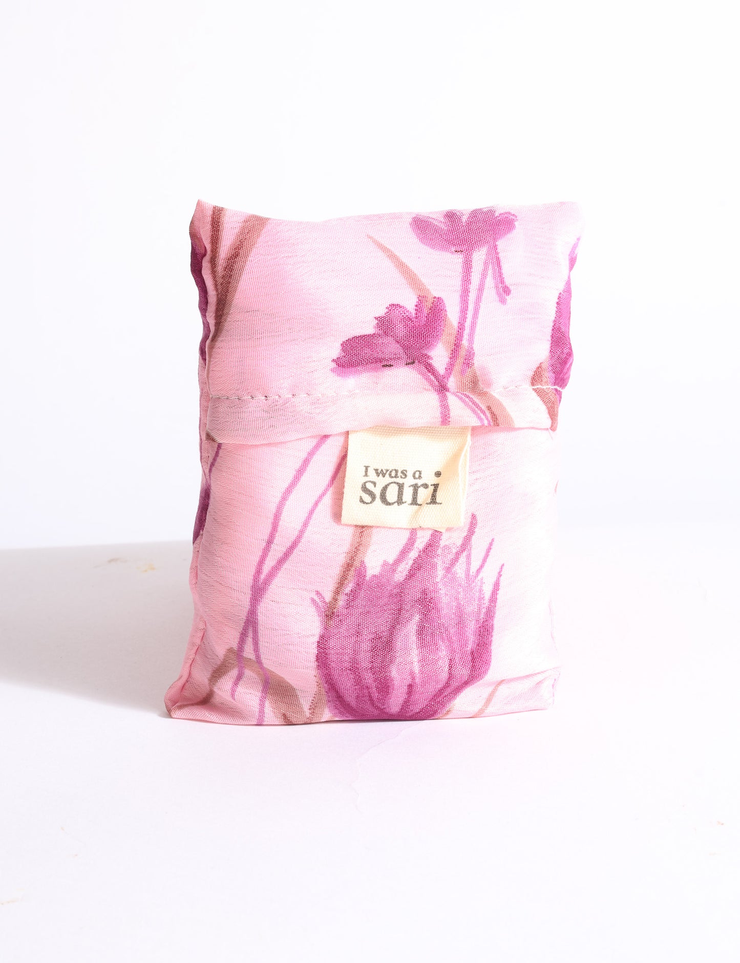 Blue reusable bag with multicolor tropical floral pattern folded with "I was a sari" label visible on front