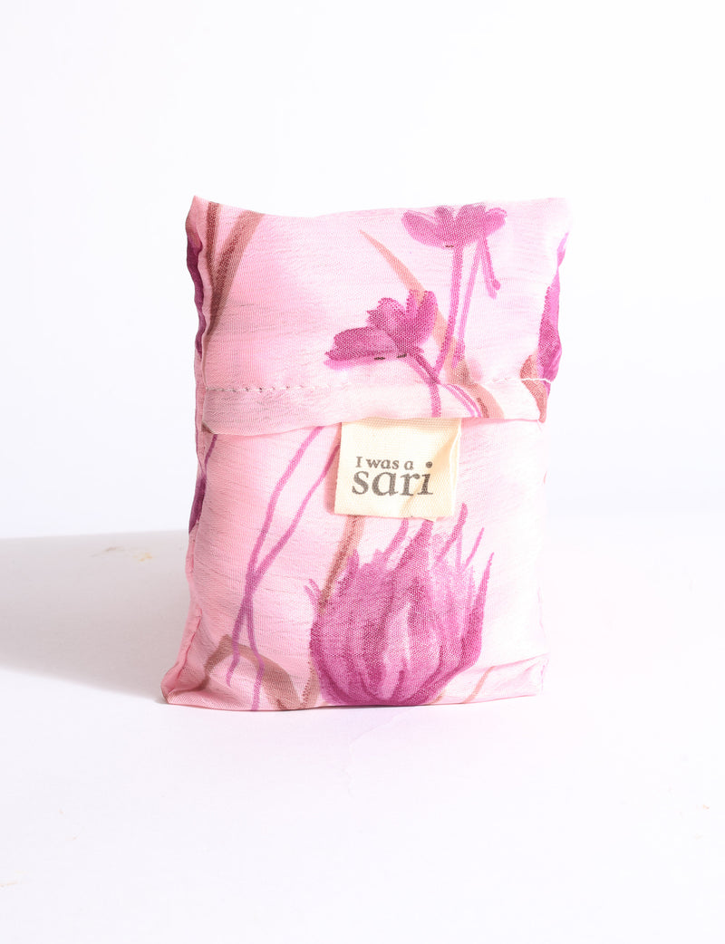 Blue reusable bag with multicolor tropical floral pattern folded with "I was a sari" label visible on front