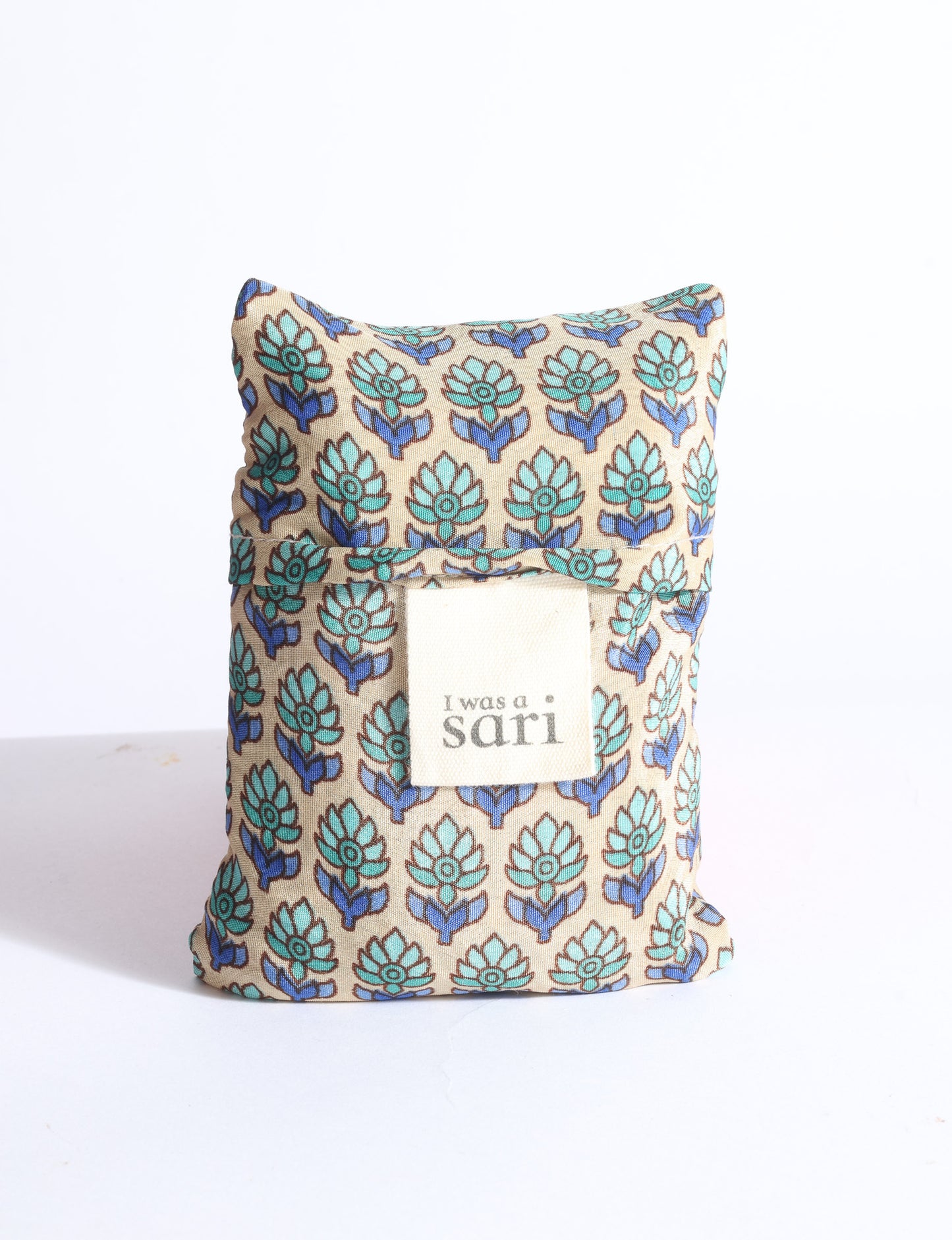 Blue reusable bag with multicolor tropical floral pattern folded with "I was a sari" label visible on front