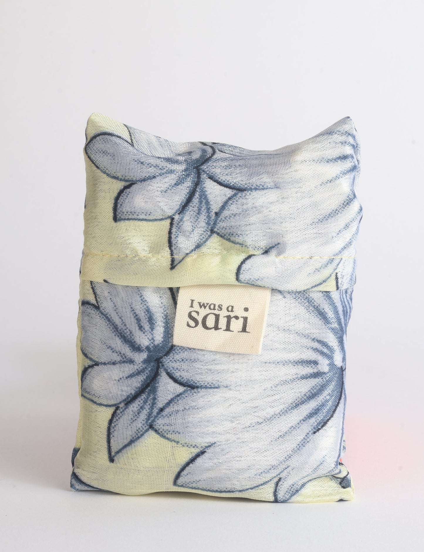 Blue reusable bag with multicolor tropical floral pattern folded with "I was a sari" label visible on front