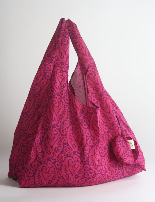 Blue reusable bag with tropical floral pattern in pink, yellow, and green, shown hanging with handles visible
