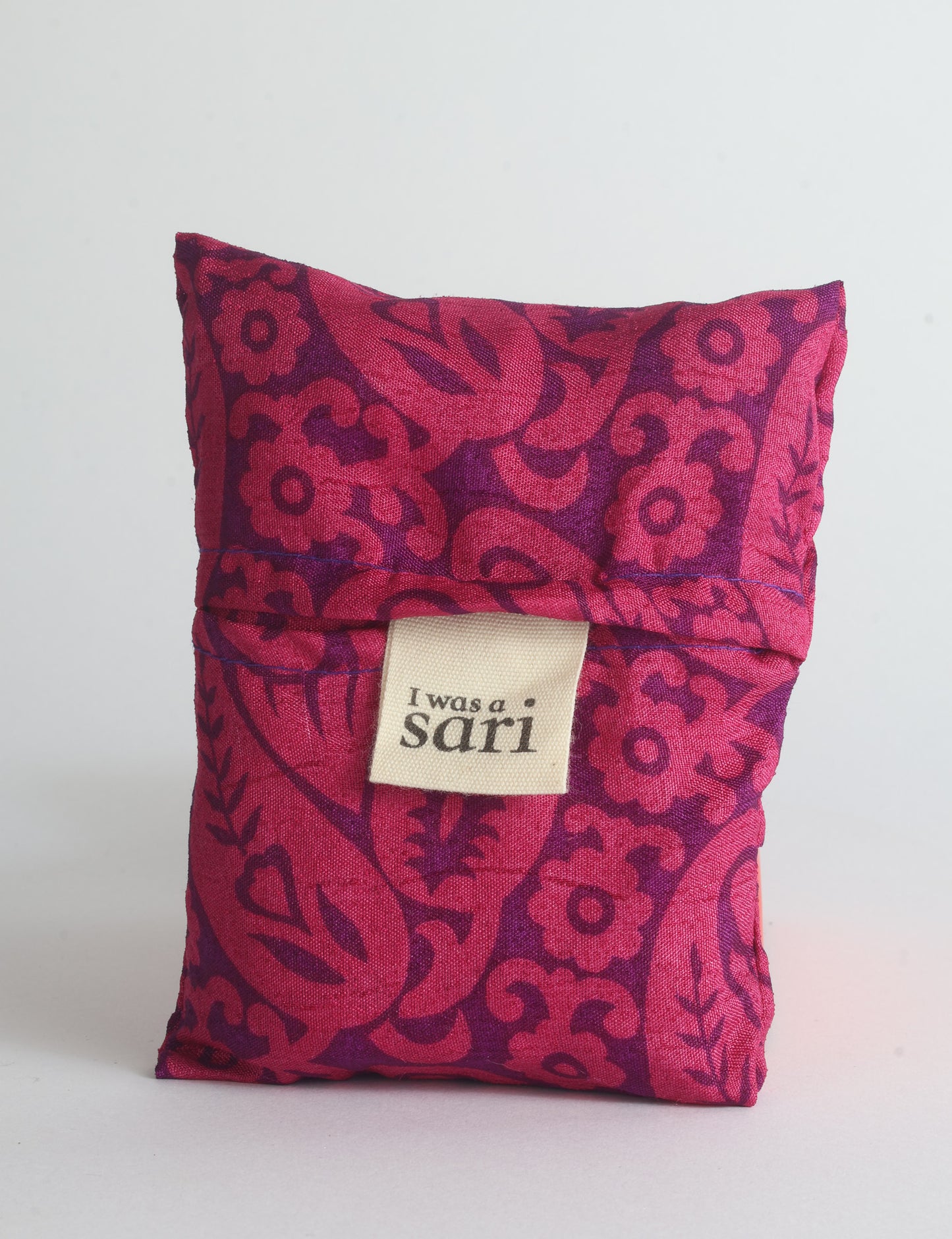 Blue reusable bag with multicolor tropical floral pattern folded with "I was a sari" label visible on front
