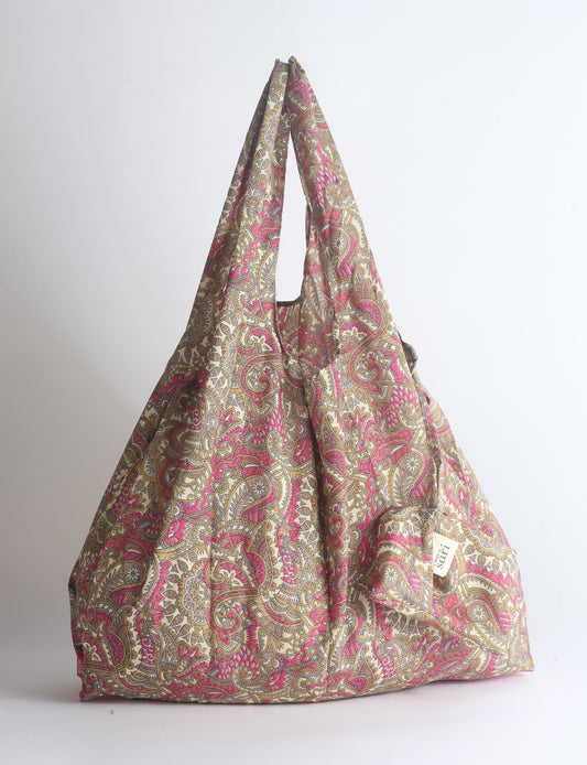 Blue reusable bag with tropical floral pattern in pink, yellow, and green, shown hanging with handles visible