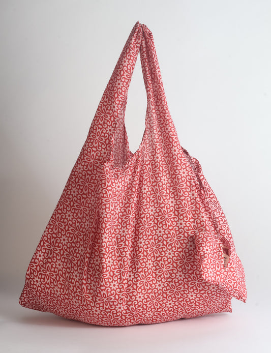 Blue reusable bag with tropical floral pattern in pink, yellow, and green, shown hanging with handles visible