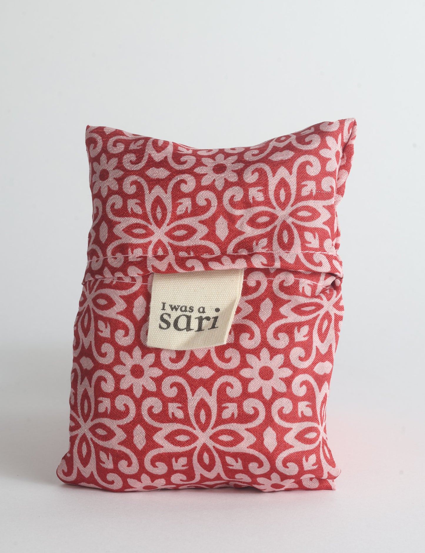 Blue reusable bag with multicolor tropical floral pattern folded with "I was a sari" label visible on front