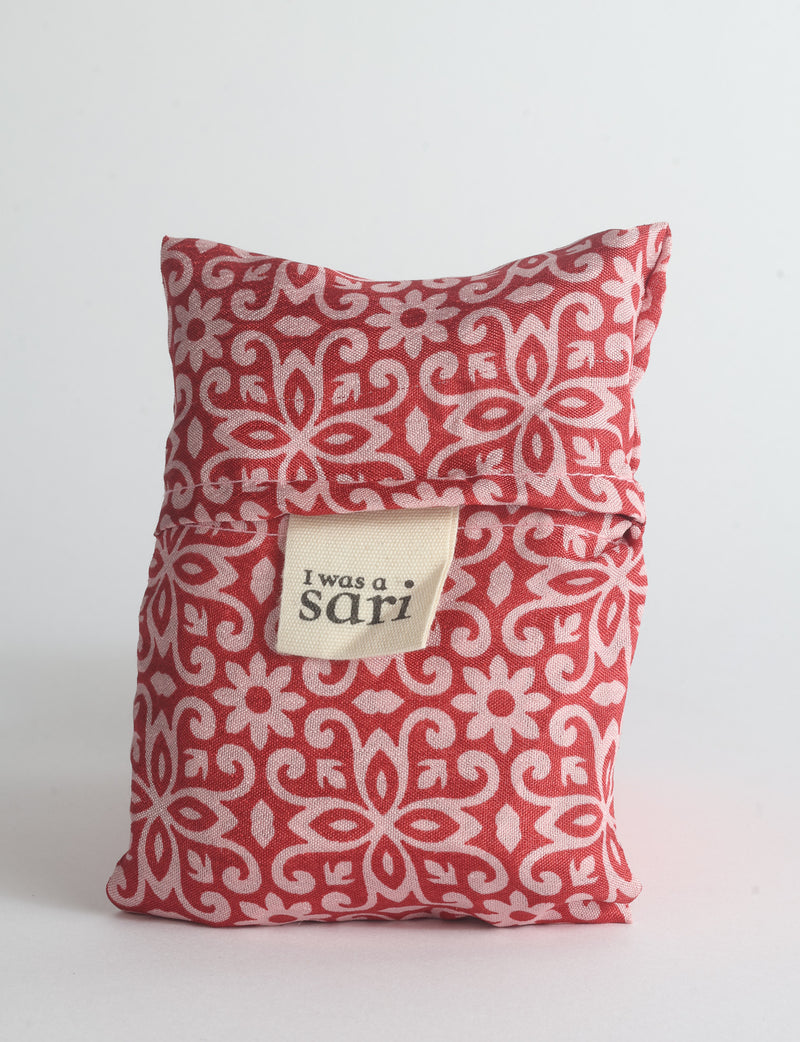 Blue reusable bag with multicolor tropical floral pattern folded with "I was a sari" label visible on front