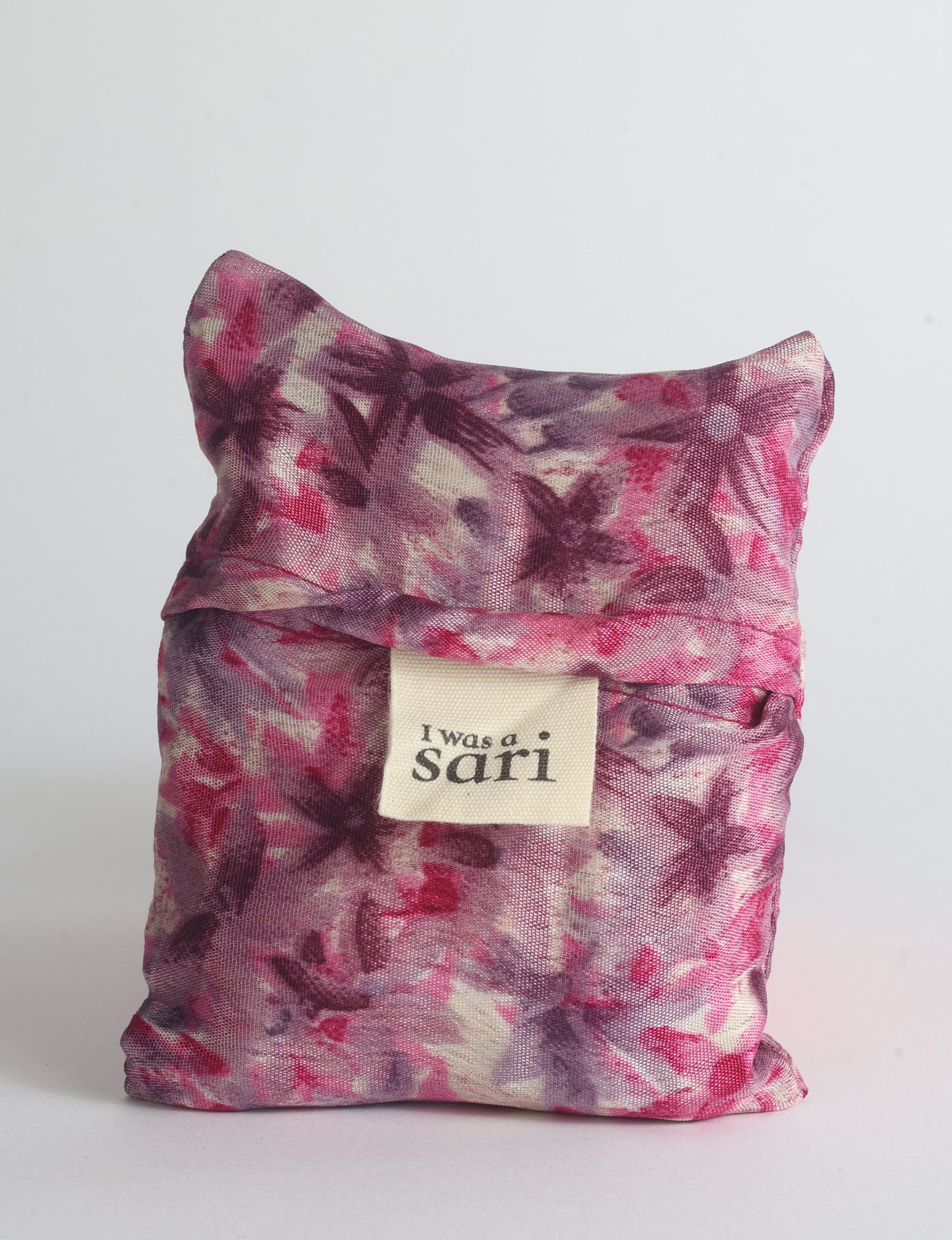 Blue reusable bag with multicolor tropical floral pattern folded with "I was a sari" label visible on front