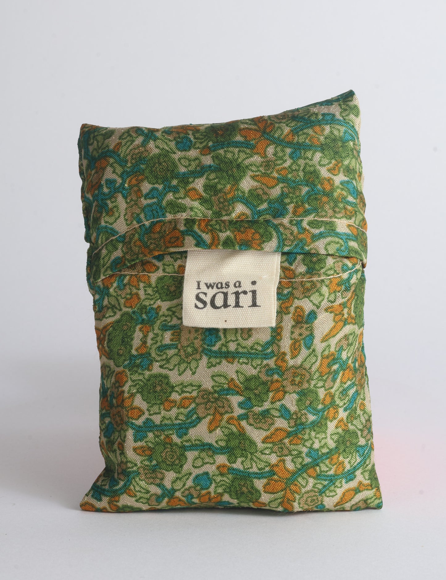 Blue reusable bag with multicolor tropical floral pattern folded with "I was a sari" label visible on front